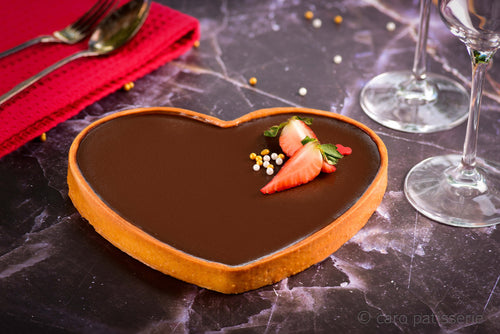 Heart shaped dark chocolate tart with fresh strawberry on top