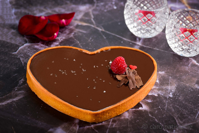 heart shaped dark chocolate tart with a raspberry on top